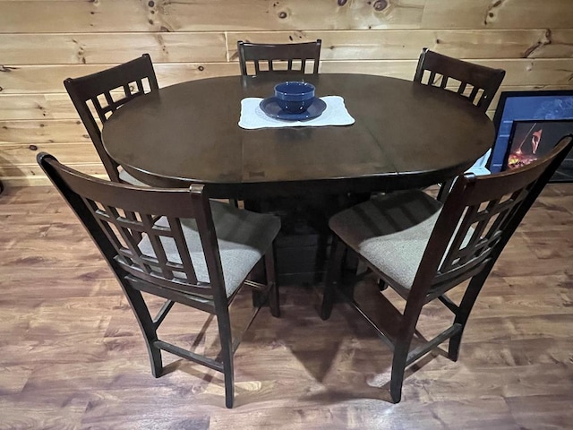 dining space with hardwood / wood-style floors and wooden walls