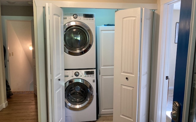 laundry area with light hardwood / wood-style flooring and stacked washer / drying machine