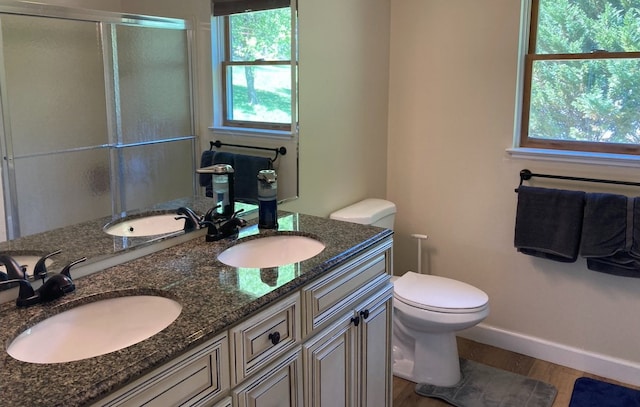 bathroom featuring hardwood / wood-style floors, vanity, toilet, and a shower with shower door