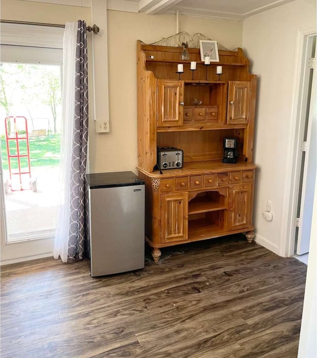 bar featuring dark hardwood / wood-style floors, a healthy amount of sunlight, crown molding, and stainless steel refrigerator