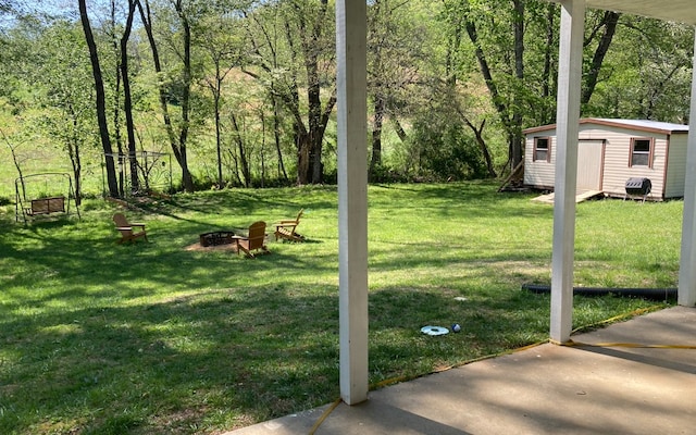 view of yard with a fire pit, a storage unit, and a patio area