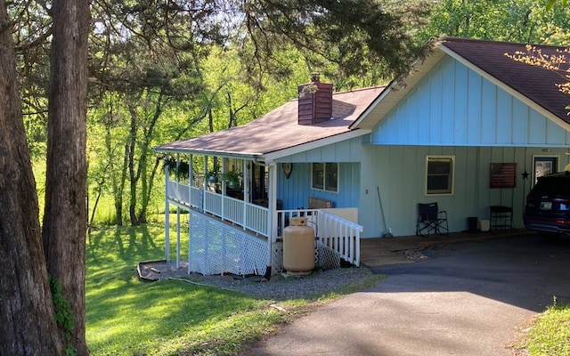 view of front of home featuring covered porch, a front lawn, and a carport