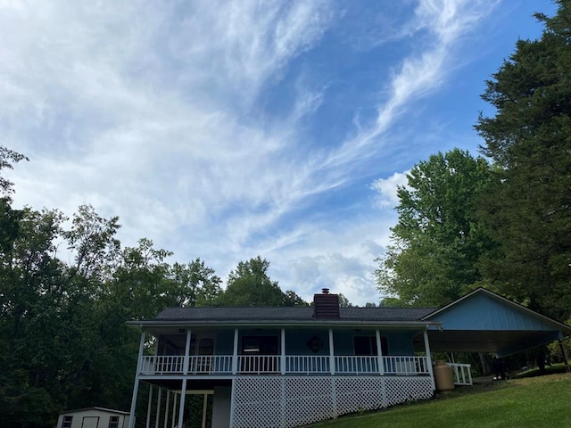 view of front of property with a carport, a storage unit, and a front lawn