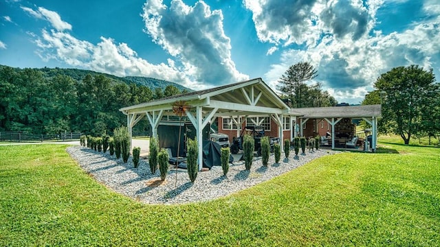 view of property's community featuring fence, a patio, a gazebo, a carport, and a lawn