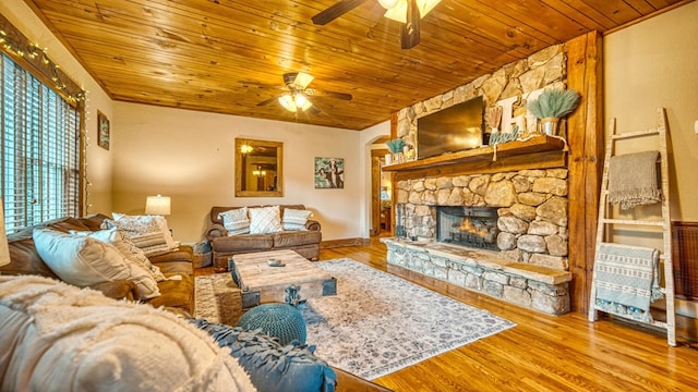 living area featuring wood ceiling, arched walkways, ceiling fan, a stone fireplace, and wood finished floors