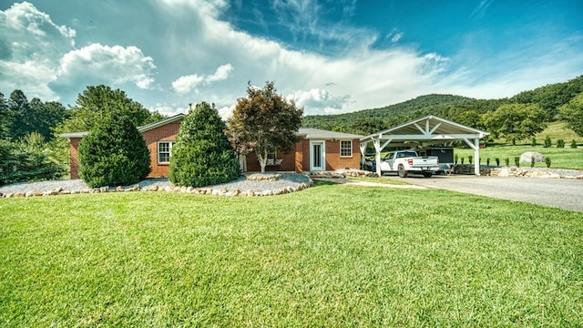 view of front of home with brick siding, concrete driveway, a detached carport, and a front lawn