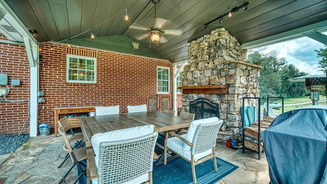 view of patio / terrace with a grill, outdoor dining area, an outdoor stone fireplace, and ceiling fan