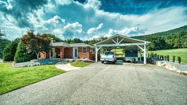 view of front of property with brick siding, a front yard, driveway, and a detached carport