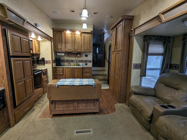kitchen with carpet, decorative light fixtures, oven, and sink