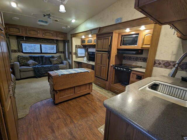 kitchen featuring dark wood-type flooring, sink, vaulted ceiling, ceiling fan, and built in microwave