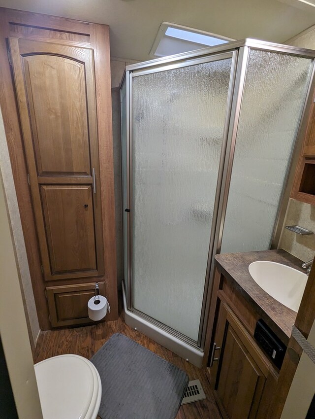 bathroom featuring toilet, a shower with door, vanity, and hardwood / wood-style flooring