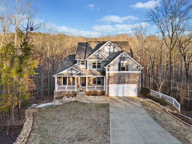 9475 Dunmoore Dr, Cumming, GA 30028 - view of front of home with an attached garage, covered porch, a view of trees, stone siding, and driveway
