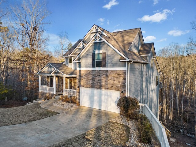 9475 Dunmoore Dr, Cumming, GA 30028 - view of front of house featuring stone siding, a garage, covered porch, and driveway