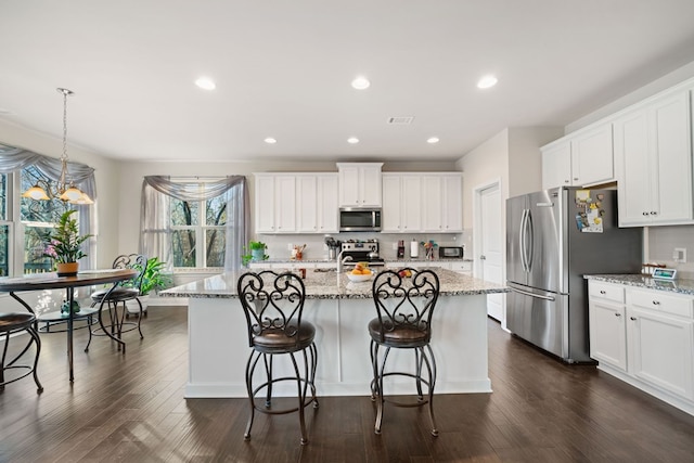 9475 Dunmoore Dr, Cumming, GA 30028 - kitchen featuring dark wood-style floors, recessed lighting, a kitchen island with sink, stainless steel appliances, and white cabinets