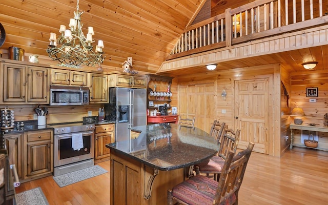 kitchen featuring stainless steel appliances, a center island, wood walls, and a breakfast bar area