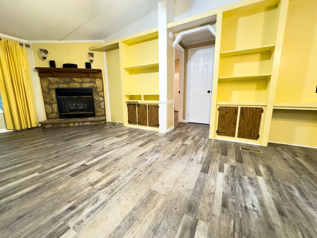 unfurnished living room with a stone fireplace, wood-type flooring, built in features, ornamental molding, and lofted ceiling