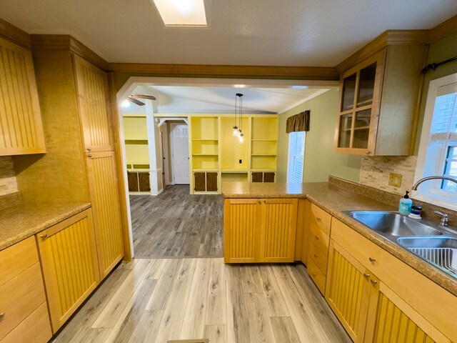 kitchen featuring light wood-type flooring, pendant lighting, crown molding, kitchen peninsula, and ceiling fan