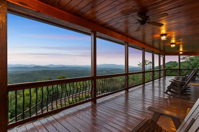 deck at dusk featuring a mountain view and ceiling fan