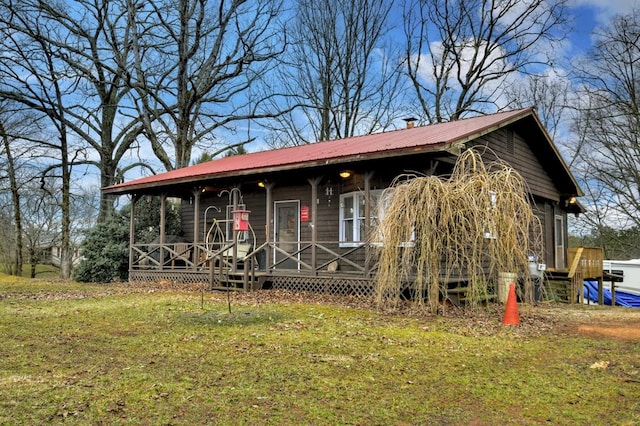 view of front of property featuring metal roof, covered porch, and a front yard