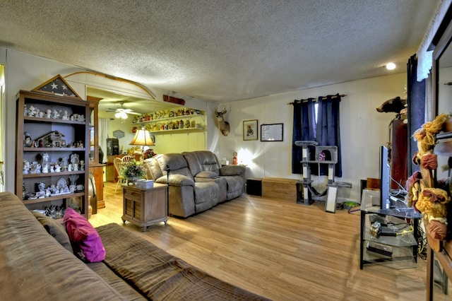 living area featuring a textured ceiling, wood finished floors, and a ceiling fan