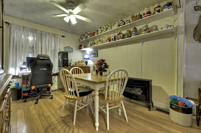 dining space featuring a ceiling fan, wood finished floors, visible vents, and a textured ceiling