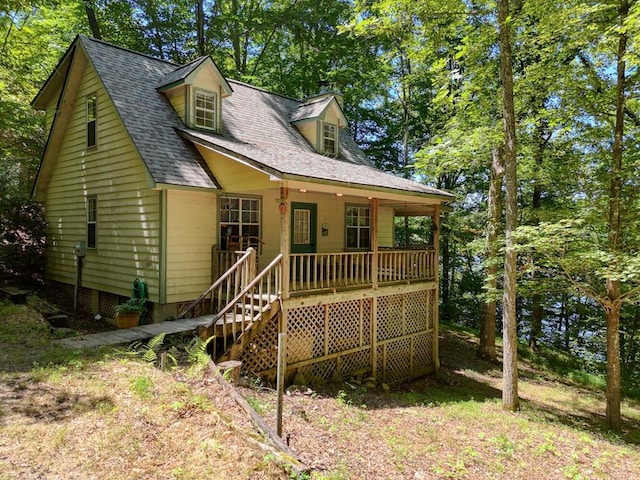 view of front of house with a porch, roof with shingles, and stairway