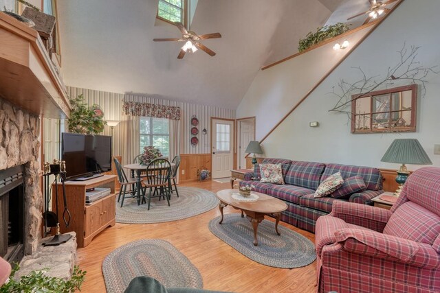 living room with ceiling fan, a wealth of natural light, light hardwood / wood-style flooring, and a fireplace