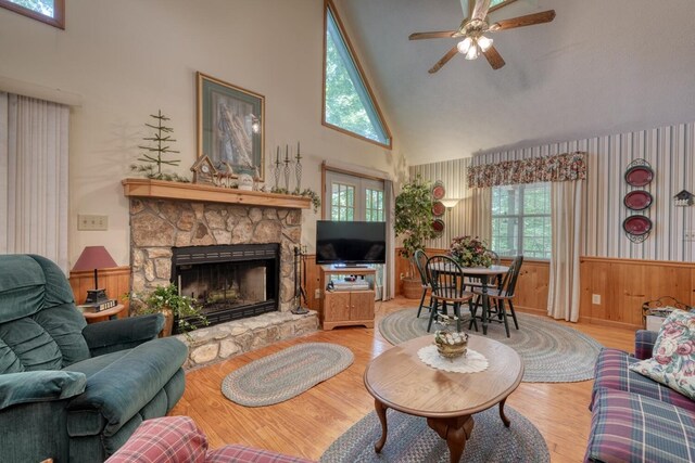 living room featuring ceiling fan, high vaulted ceiling, light hardwood / wood-style flooring, and a fireplace