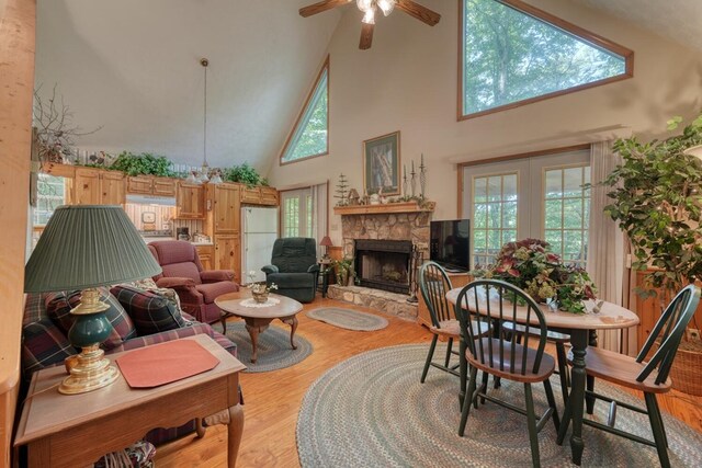 living room with ceiling fan, high vaulted ceiling, light hardwood / wood-style flooring, and a fireplace