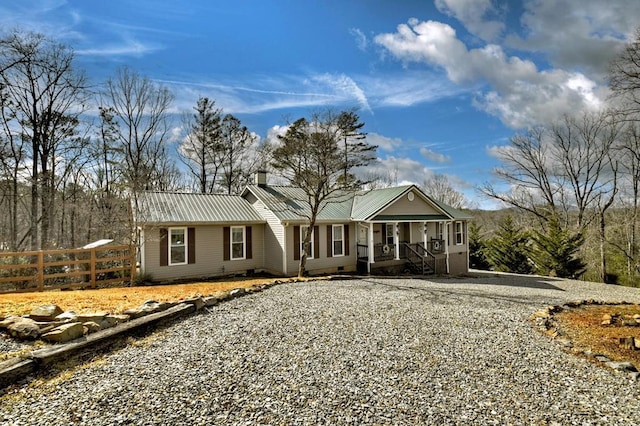 single story home featuring fence, driveway, a porch, a chimney, and metal roof