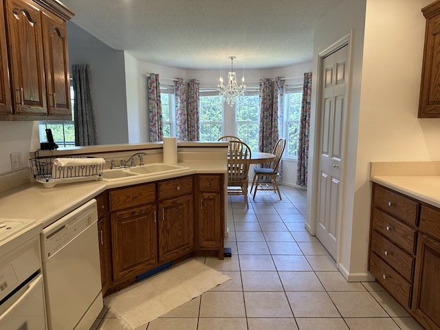 kitchen with sink, dishwasher, a notable chandelier, and light tile patterned floors