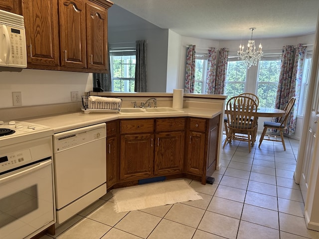 kitchen with white appliances, light tile patterned floors, an inviting chandelier, hanging light fixtures, and sink