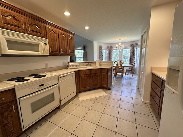 kitchen with sink, an inviting chandelier, light tile patterned floors, and white appliances