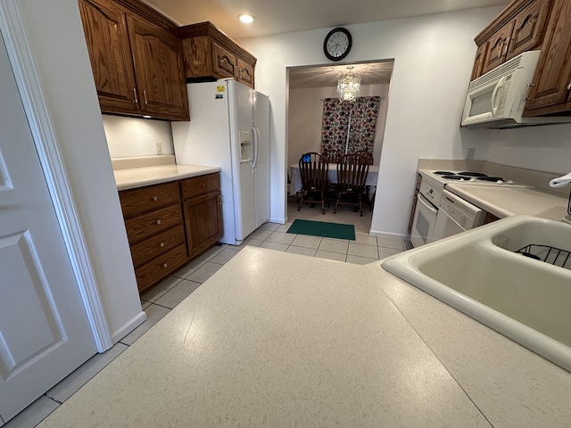 kitchen featuring dark brown cabinets, white appliances, and light tile patterned floors