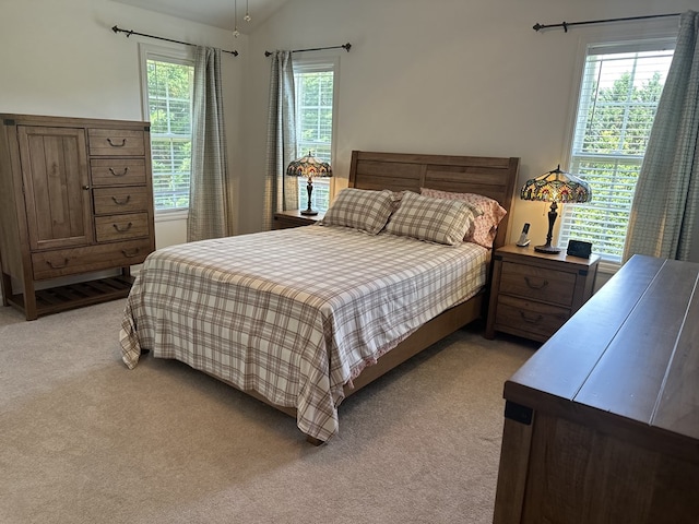 bedroom featuring light colored carpet, vaulted ceiling, and multiple windows