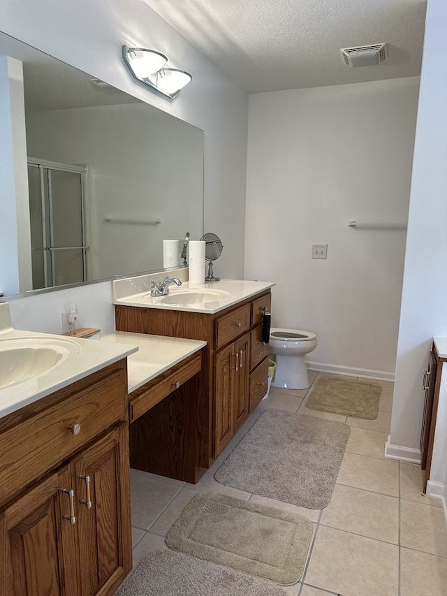 bathroom featuring tile patterned floors, double sink vanity, toilet, and a textured ceiling