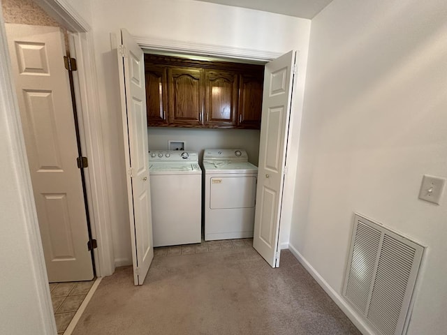 laundry area featuring cabinets, light colored carpet, and washing machine and clothes dryer