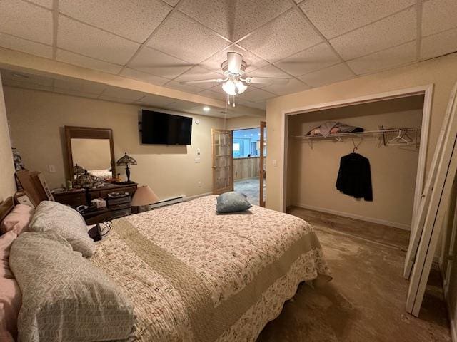 bedroom featuring ceiling fan, a closet, carpet floors, and a paneled ceiling