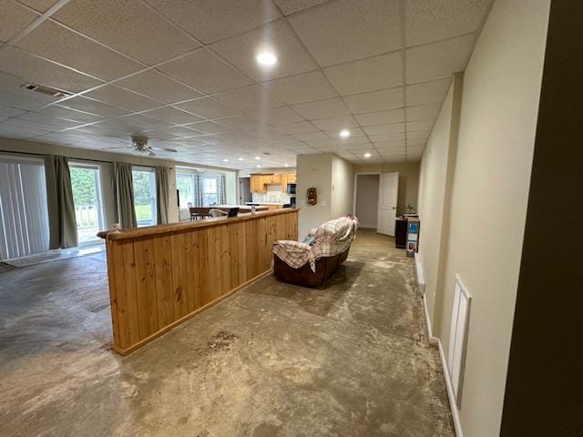 interior space with concrete flooring, ceiling fan, and a paneled ceiling