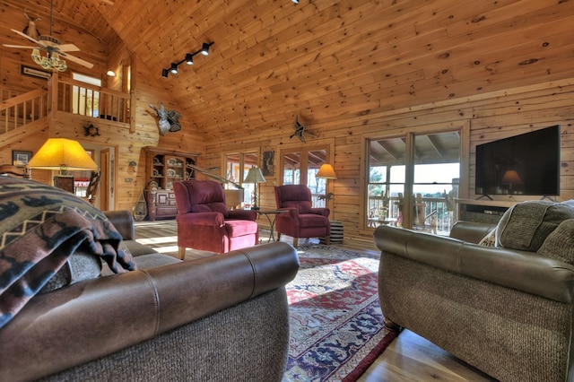 living room featuring ceiling fan, high vaulted ceiling, wooden walls, wood ceiling, and light wood-type flooring