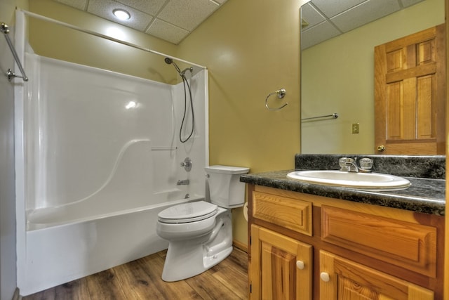 full bathroom featuring a drop ceiling, bathing tub / shower combination, wood-type flooring, toilet, and vanity