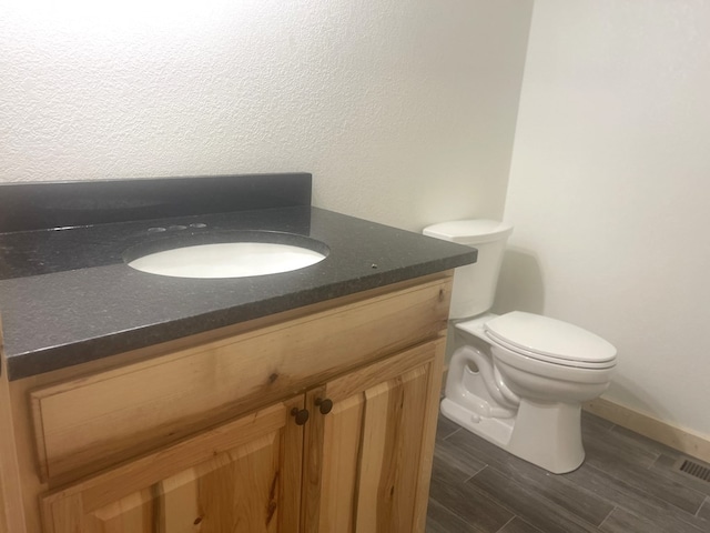 bathroom featuring toilet, vanity, and hardwood / wood-style flooring