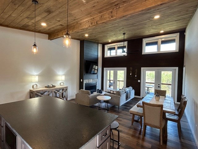 interior space with a large fireplace, french doors, hanging light fixtures, dark hardwood / wood-style floors, and wood ceiling