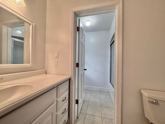 full bath featuring toilet, a textured ceiling, vanity, and a shower with shower door