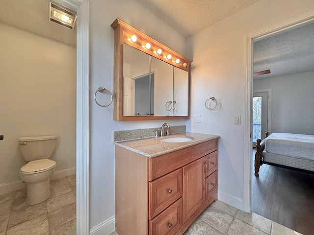 bathroom featuring toilet, ensuite bathroom, a textured ceiling, baseboards, and vanity