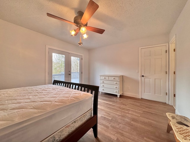 bedroom featuring access to exterior, a textured ceiling, wood finished floors, french doors, and ceiling fan