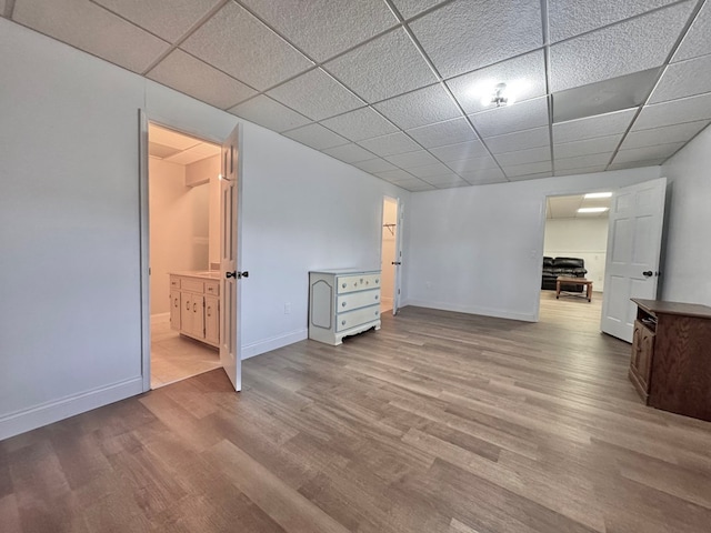 interior space featuring baseboards, a paneled ceiling, wood finished floors, and ensuite bathroom