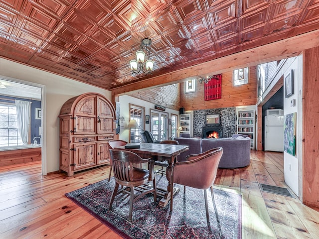 dining area with a chandelier, light wood-style flooring, a fireplace, and an ornate ceiling