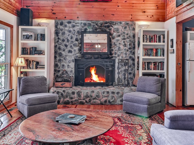 living room with built in features, wood-type flooring, a stone fireplace, and wooden ceiling