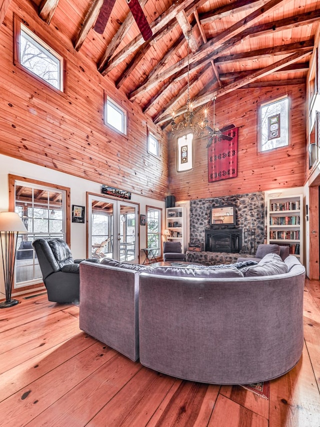 living room featuring wood ceiling, french doors, light wood-type flooring, beamed ceiling, and a wood stove